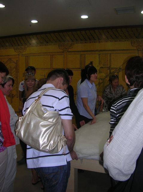 Довольные туристы принимают участие в изготовлении шёлкового одеяла