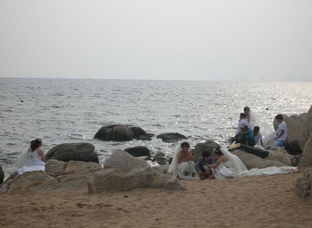 Уставшие женихи и невесты после фотосессии на морском побережье Циньхуандао